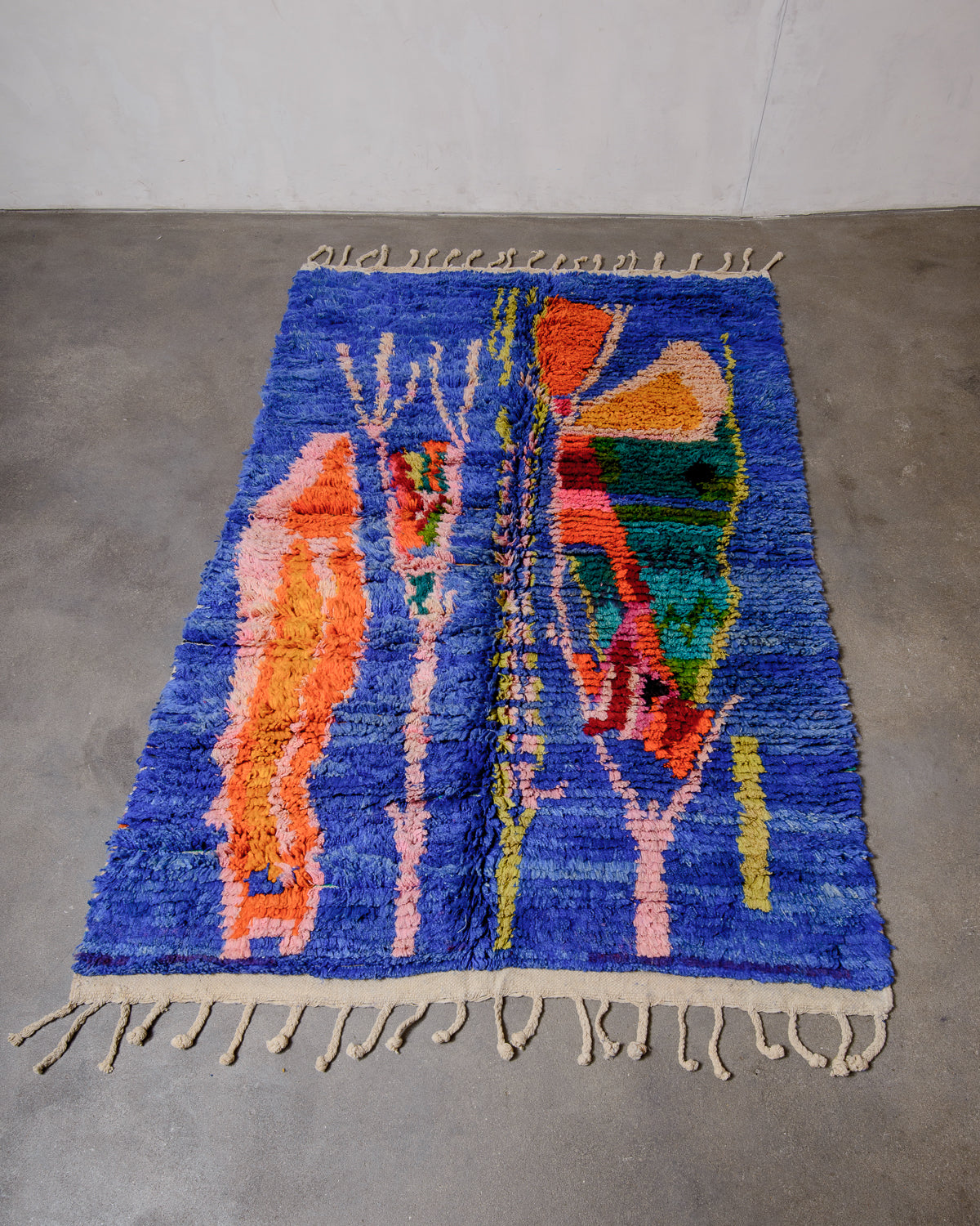 Berberlin vintage boujad rug in colourful wool laying flat on concrete floor.